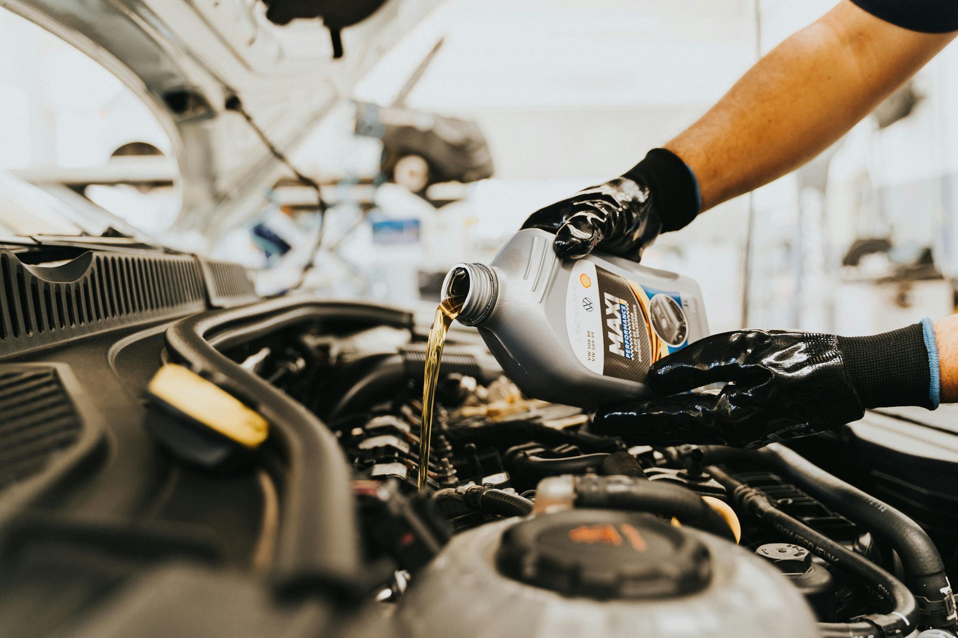 Person pouring motor oil into a car engine during an oil change.