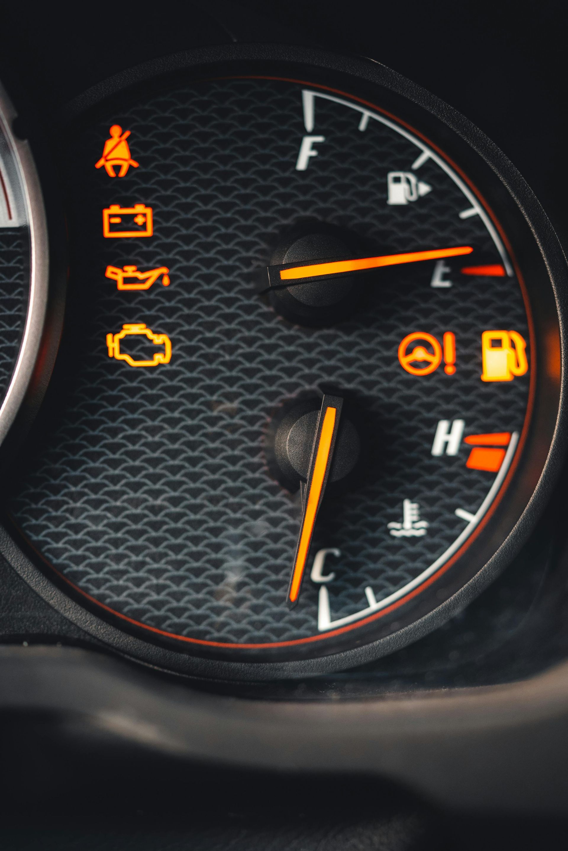 Car dashboard gauge cluster with several amber warning lights illuminated and the fuel and temperature needles visible