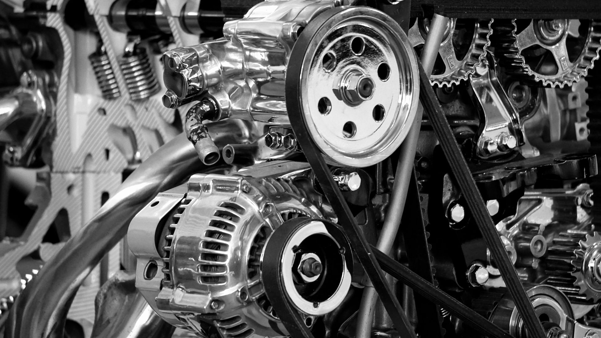 Close-up of a shiny chrome engine with belts, pulleys, and gears, emphasizing mechanical details.