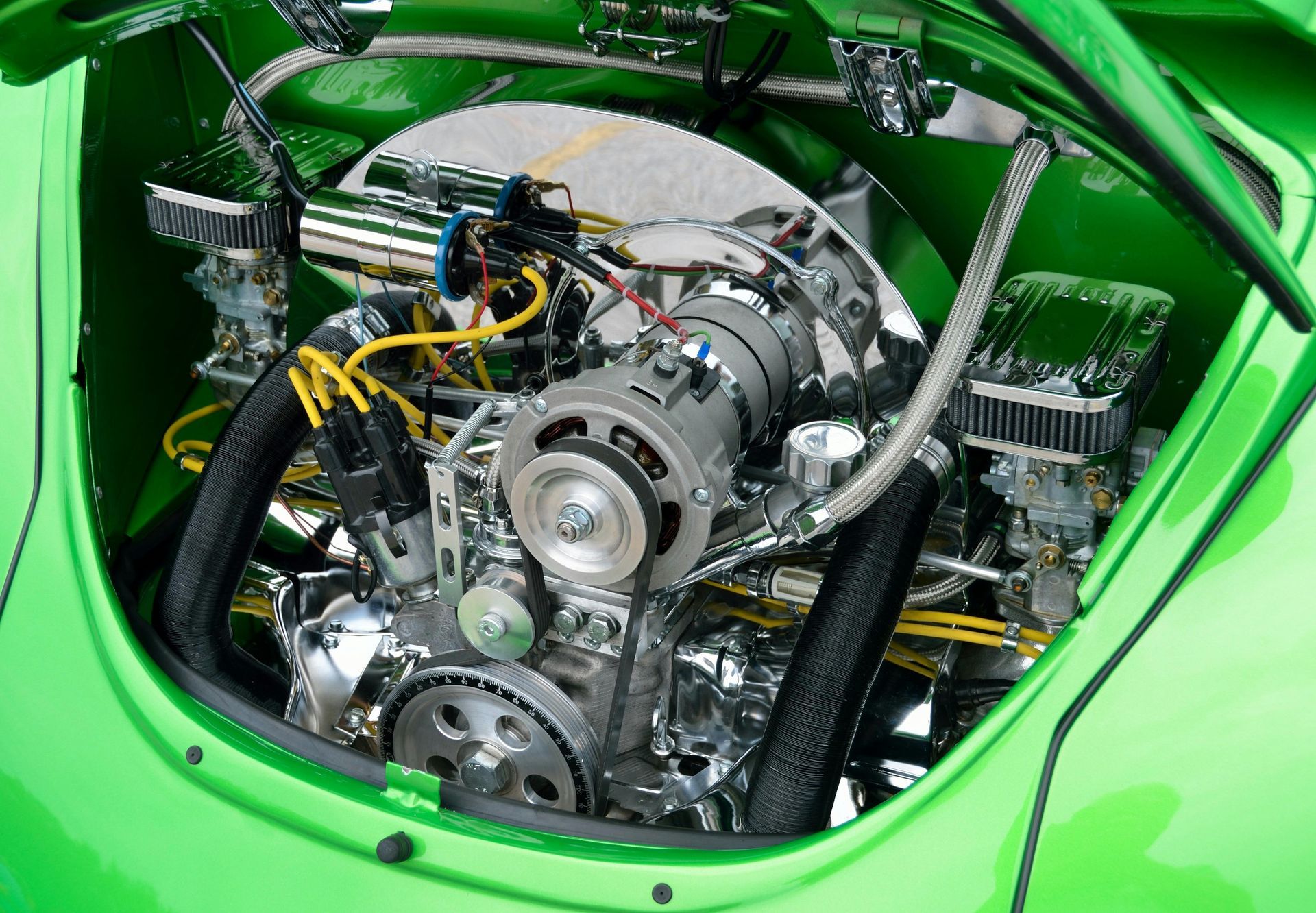 Shiny chrome engine in a green classic Volkswagen Beetle.