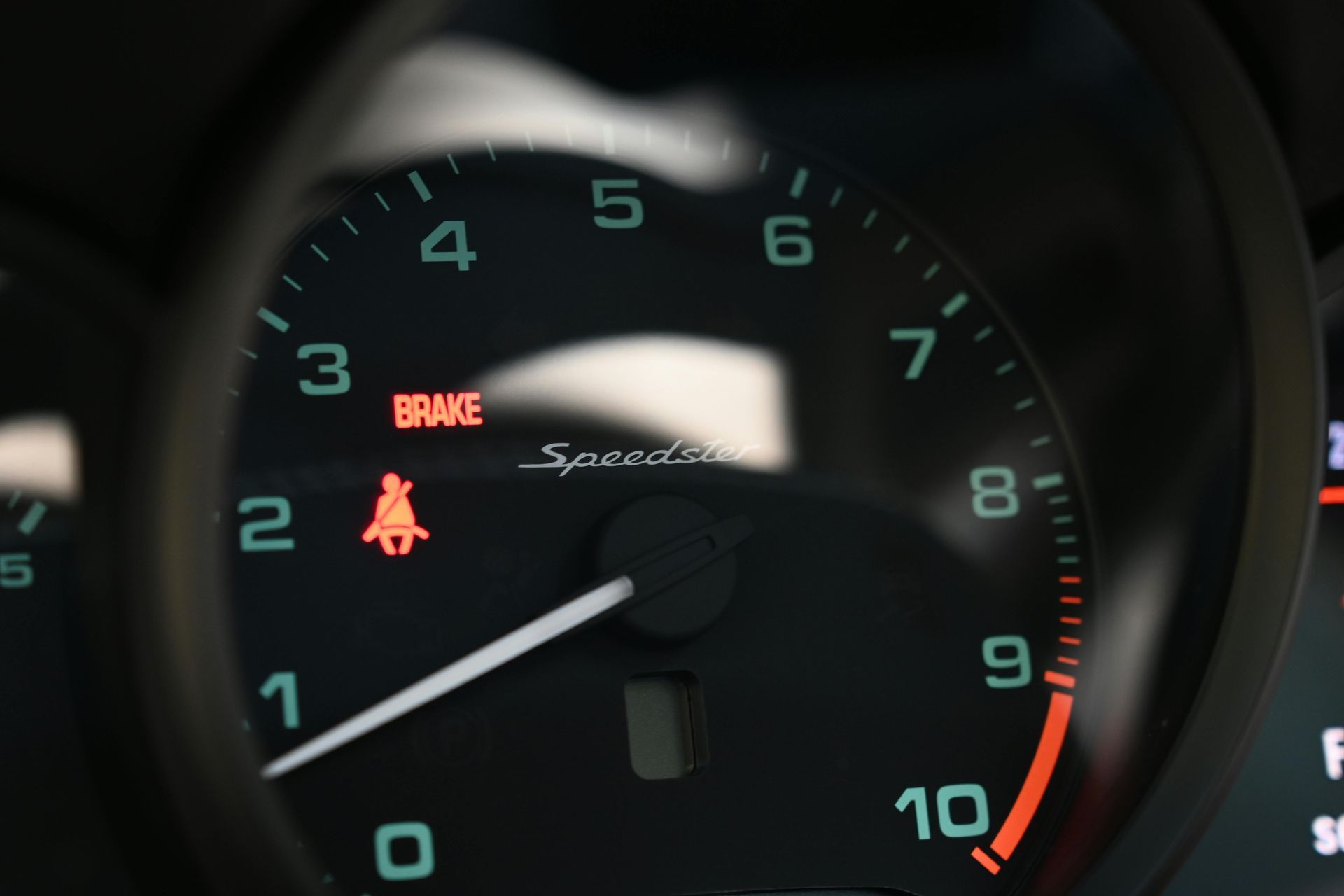 Close-up of a car's dashboard with the speedometer showing a red 
